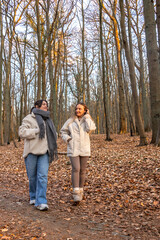 Two female friends on a walk in the forest. Friends walking through the forest. People in nature.