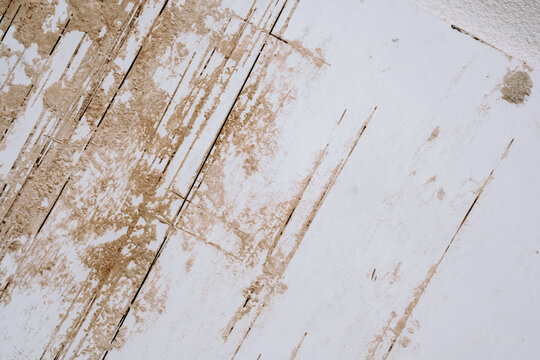 White wall with beige peeling texture and vertical damage marks from aging