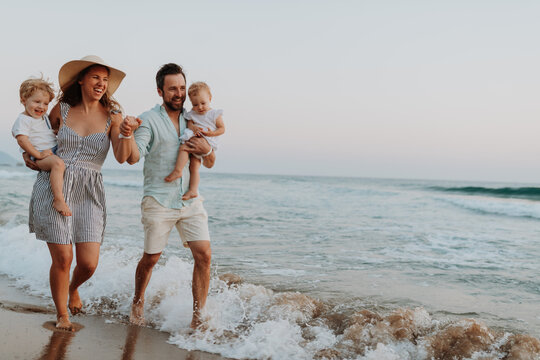 Young family walking on sandy shore during summer beach holiday. - Powered by Adobe