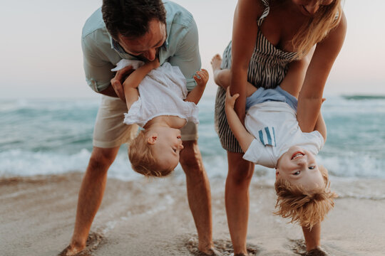 Fototapeta A young family with two toddler children having fun on beach on summer holiday.