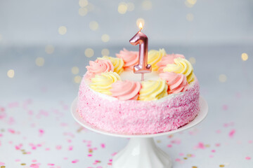 Delightful one-year birthday cake with pink and yellow frosting and a candle