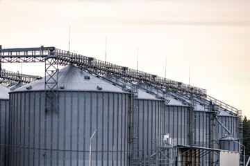 Large metallic storage tanks and silos are situated within an industrial complex, showcasing a...