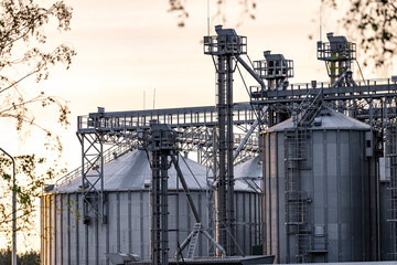 Large metallic storage tanks and silos are situated within an industrial complex, showcasing a...