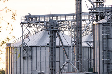 Large metallic storage tanks and silos are situated within an industrial complex, showcasing a...