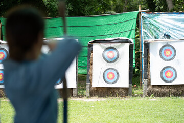 Asian woman is holds her bow for shooting arrow to the target, selective focus.