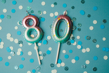 Celebration with sparkling 80th birthday candles on vibrant blue background