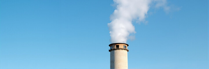 Industrial smoke stack emitting white smoke against clear blue sky.  Factory chimney with pollution plume on bright sunny day.  Image suitable for environmental reports or industrial design projects.