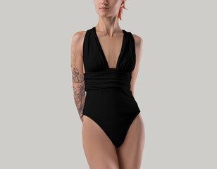 Mockup of a black monokini with a neckline on a red-haired girl with a tattoo, front view, isolated...