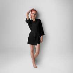 Mockup of a black silk robe on a slender red-haired girl with a tattoo, front view, short kimono with a belt, isolated on background.