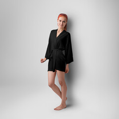 Mockup of a black silk robe with a belt on a slender red-haired girl with a tattoo, front view, short kimono, isolated on background.