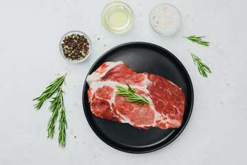 Pork steak with rosemary on black plate with spices