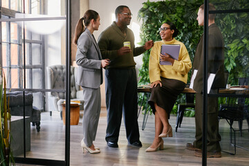 Group of young adult and middle aged multiethnic business professionals discussing project in...