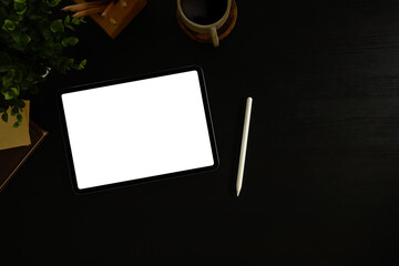 Home office desk with digital tablet, wireless headphones, and potted plant
