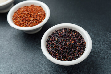 Three types of rice in bowls on dark background top view