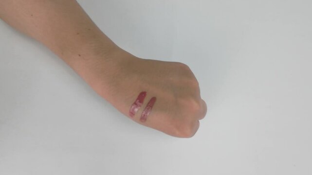 Smearing Liquid Lipstick on Hand in Bright Studio