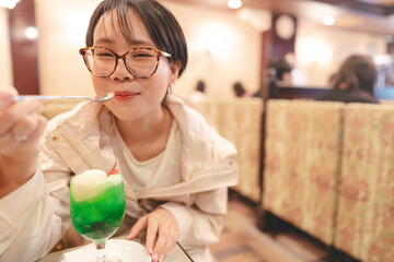 Young adult asian japanese woman eating icecream melon soda cafe menu relax in kissaten japan style retro coffee shop