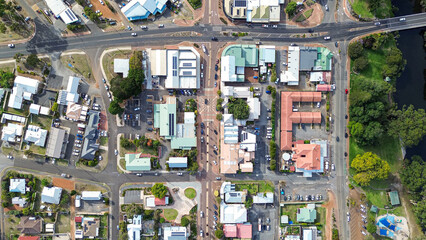 Top down Arial view of a small rural town centre with cars on the road, roof tops of homes and businesses, a river with park and trees. Main road with 4 Way intersection. Denmark Western Australia  © Sam Jeffs