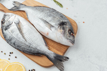 Raw dorado fish with ingredients on wooden cutting board over white background