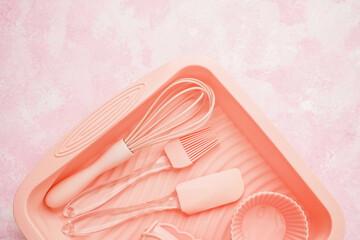 Closeup of pink silicone baking utensils in tray on pink background