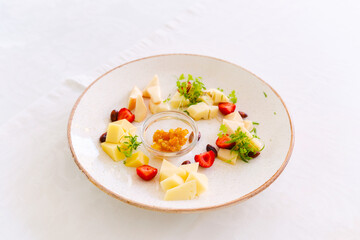 Fresh cheese platter with fruits and a flavorful chutney on a white table