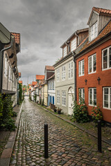Narrow cobblestone alley lined with historic, colorful houses in the old town of Flensburg, Schleswig-Holstein, Germany
