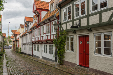 Narrow cobblestone alley lined with historic, colorful houses in the old town of Flensburg, Schleswig-Holstein, Germany