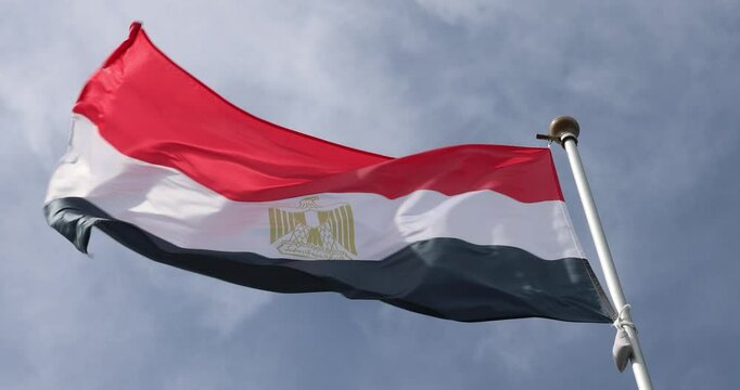 4K video The flag of Egypt is waving against the background of a clear blue sky with white clouds. Close-up, perfect for news.