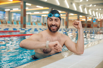Man having a workout in the swimming pool and looking at his watch