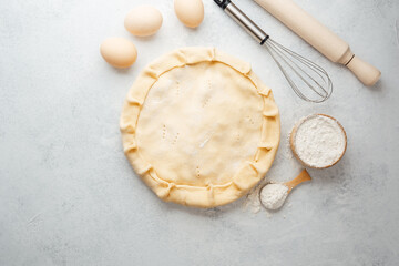 Pie crust preparation with eggs and flour on a kitchen countertop