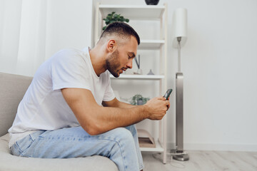 Pensive man sitting on the couch, experiencing digital detox while engaging in emotional...
