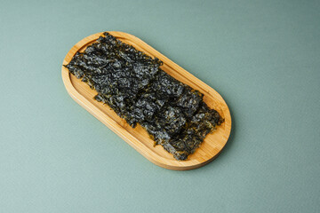 roasted seaweed snack on wooden tray over green background