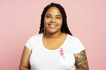 Young woman smiling and wearing a pink ribbon for breast cancer awareness