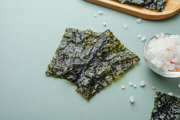 Crispy nori seaweed snack with salt on green background