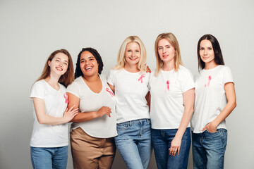 Obraz premium Diverse women wearing pink ribbons are embracing for breast cancer awareness