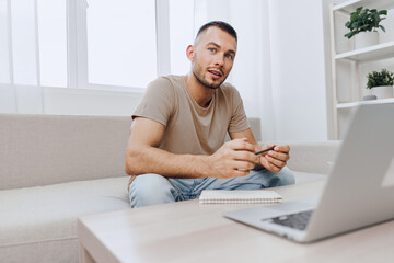 Thoughtful man working at home, engaged in online tasks with a notebook at hand. Modern workspace...