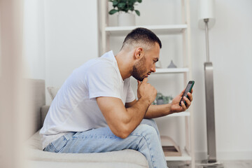 Pensive man engrossed in smartphone, showcasing modern lifestyle and digital connection with a...