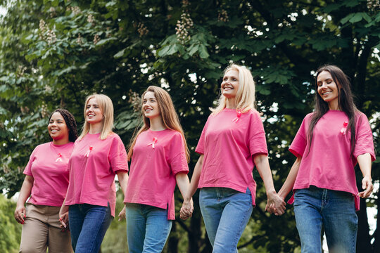 Women holding hands wearing pink ribbons are walking for breast cancer awareness