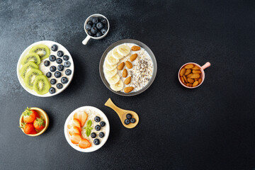 Assorted breakfast oatmeal bowls with fruits chia seeds and almonds on black background