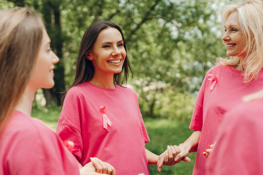 Women wearing pink ribbons holding hands supporting breast cancer awareness