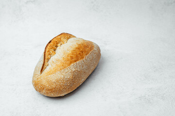 Freshly baked bread roll on a light textured background in a simple setting