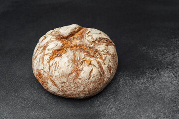 Freshly baked round artisan bread resting on a dark surface