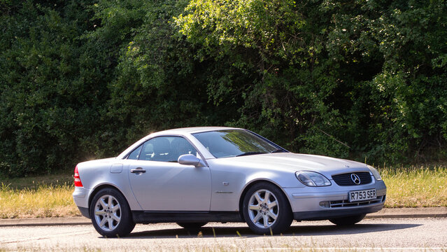 Milton Keynes,Bucks,UK - June 16th 2025:  1998 silver Mercedes-Benz slk classic car driving on a British road