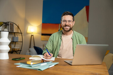 Freelancer working from home using laptop and notebook