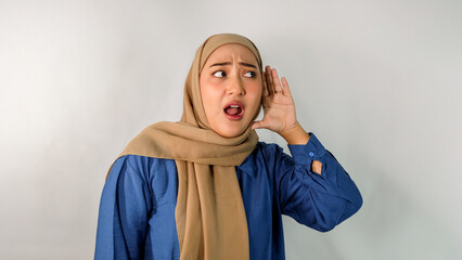 Beautiful young Asian Muslim woman wearing hijab and blue dress, curious and inquisitive, trying to...
