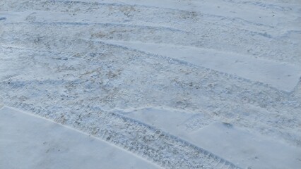 A close-up view of a snow-covered surface with distinct, parallel tracks or grooves, likely left by...