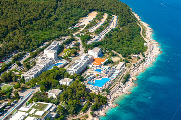 A stunning aerial view of a luxurious coastal resort nestled between dense pine forests and the...
