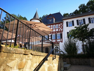 Sanierte alte Häuser in Naturfarben mit Fachewerk und Sonnenschirm vor blauem Himmel im...