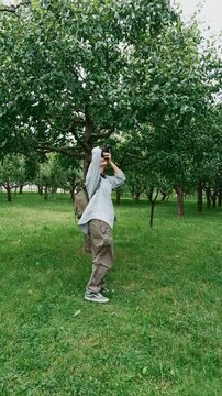 young female photographer taking photos of trees in park bright natural outdoor setting creative nature concept
