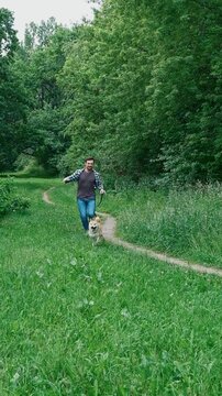 young man in plaid shirt playing training petting hugging and kissing his dog during summer park walk happy loving companionship concept lifestyle	