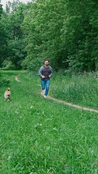 young man in plaid shirt playing training petting hugging and kissing his dog during summer park walk happy loving companionship concept lifestyle	